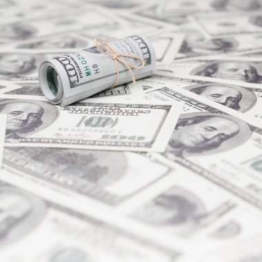 Bize dolar haddelenmiş ve grup ile sıkılaştırılmış bir sürü Amerikan banknotları bulanık arka plan ile yatıyor. Para büyük miktarda