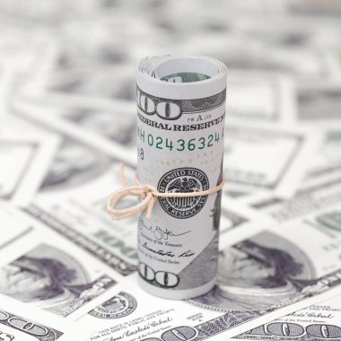 Bize dolar haddelenmiş ve grup ile sıkılaştırılmış bir sürü Amerikan banknotları bulanık arka plan ile yatıyor. Para büyük miktarda