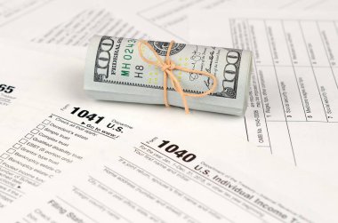 Vergi formları yüz dolarlık faturaları rulo yakın yatıyor. Gelir vergisi iadesi. Vergi kavramı ödeme zamanı. 1040 1041 1120 ve 1065 boş boş formlar