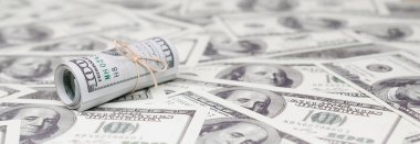 Bize dolar haddelenmiş ve grup ile sıkılaştırılmış bir sürü Amerikan banknotları bulanık arka plan ile yatıyor. Para büyük miktarda