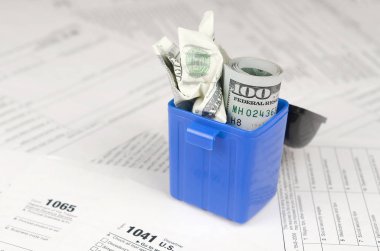 Birçok Amerikan vergisi boş formları ve çöp kutusunda yüz dolarlık banknotu. Vergiler kavramı ödemek için para kaybı
