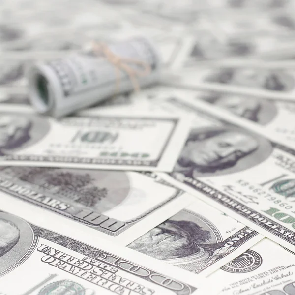 Bize dolar haddelenmiş ve grup ile sıkılaştırılmış bir sürü Amerikan banknotları bulanık arka plan ile yatıyor. Para büyük miktarda