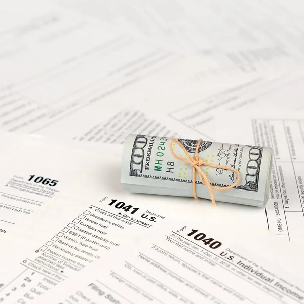 Vergi formları yüz dolarlık faturaları rulo yakın yatıyor. Gelir vergisi iadesi. Vergi kavramı ödeme zamanı. 1040 1041 1120 ve 1065 boş boş formlar