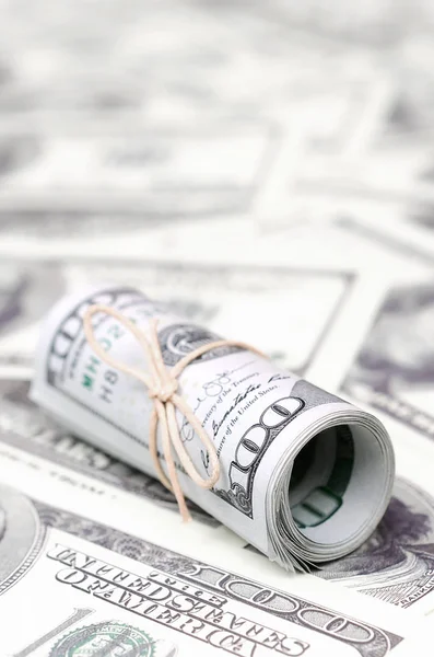 Bize dolar haddelenmiş ve grup ile sıkılaştırılmış bir sürü Amerikan banknotları bulanık arka plan ile yatıyor. Para büyük miktarda