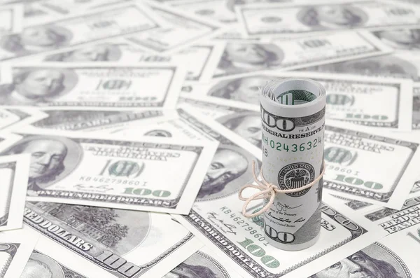 Bize dolar haddelenmiş ve grup ile sıkılaştırılmış bir sürü Amerikan banknotları bulanık arka plan ile yatıyor. Para büyük miktarda