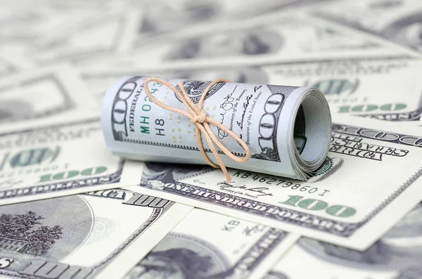 Bize dolar haddelenmiş ve grup ile sıkılaştırılmış bir sürü Amerikan banknotları bulanık arka plan ile yatıyor. Para büyük miktarda