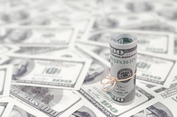 Bize dolar haddelenmiş ve grup ile sıkılaştırılmış bir sürü Amerikan banknotları bulanık arka plan ile yatıyor. Para büyük miktarda