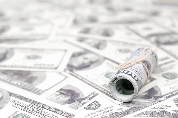Bize dolar haddelenmiş ve grup ile sıkılaştırılmış bir sürü Amerikan banknotları bulanık arka plan ile yatıyor. Para büyük miktarda