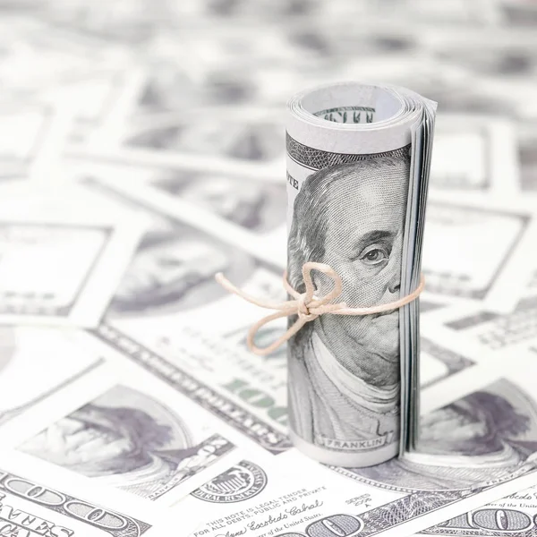 Bize dolar haddelenmiş ve grup ile sıkılaştırılmış bir sürü Amerikan banknotları bulanık arka plan ile yatıyor. Para büyük miktarda