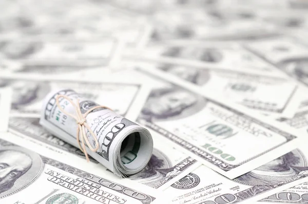 Bize dolar haddelenmiş ve grup ile sıkılaştırılmış bir sürü Amerikan banknotları bulanık arka plan ile yatıyor. Para büyük miktarda