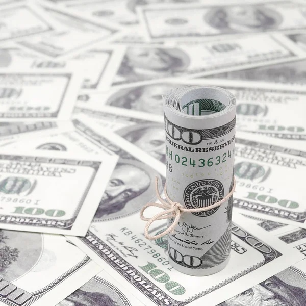 Bize dolar haddelenmiş ve grup ile sıkılaştırılmış bir sürü Amerikan banknotları bulanık arka plan ile yatıyor. Para büyük miktarda