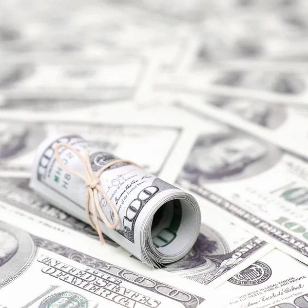 Bize dolar haddelenmiş ve grup ile sıkılaştırılmış bir sürü Amerikan banknotları bulanık arka plan ile yatıyor. Para büyük miktarda
