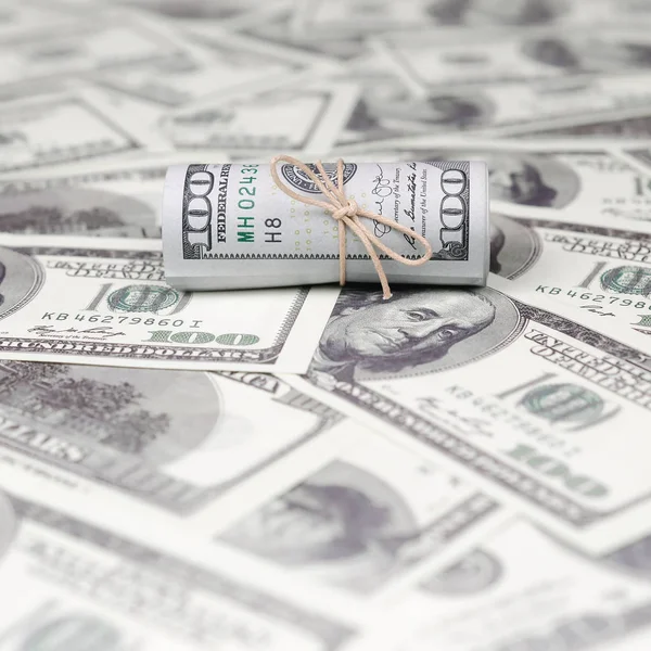 Bize dolar haddelenmiş ve grup ile sıkılaştırılmış bir sürü Amerikan banknotları bulanık arka plan ile yatıyor. Para büyük miktarda