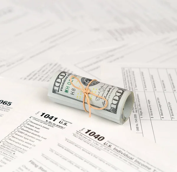 Vergi formları yüz dolarlık faturaları rulo yakın yatıyor. Gelir vergisi iadesi. Vergi kavramı ödeme zamanı. 1040 1041 1120 ve 1065 boş boş formlar