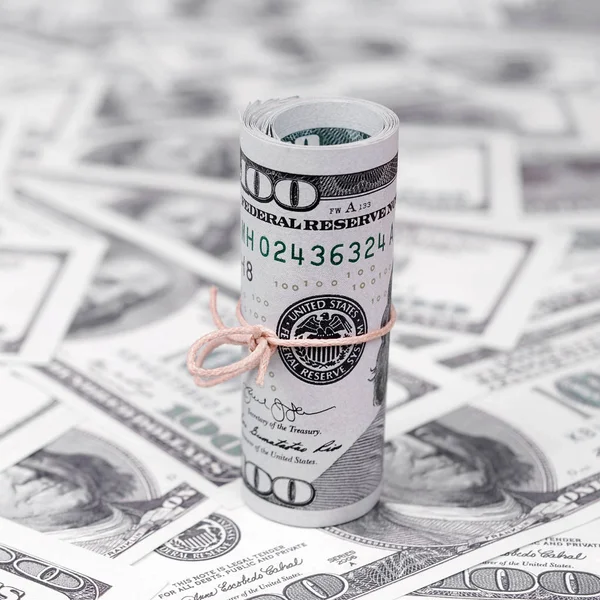 Bize dolar haddelenmiş ve grup ile sıkılaştırılmış bir sürü Amerikan banknotları bulanık arka plan ile yatıyor. Para büyük miktarda