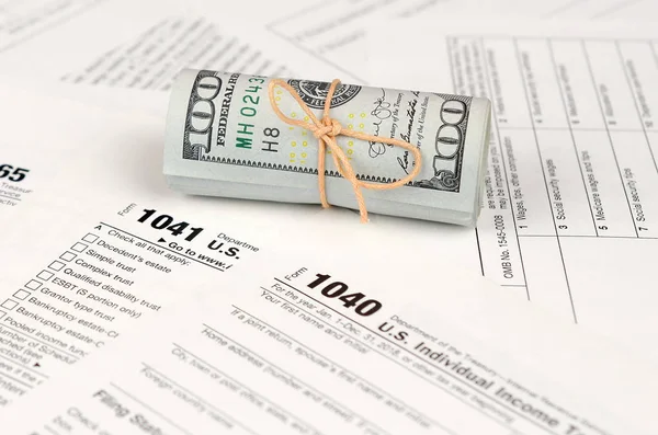 Vergi formları yüz dolarlık faturaları rulo yakın yatıyor. Gelir vergisi iadesi. Vergi kavramı ödeme zamanı. 1040 1041 1120 ve 1065 boş boş formlar