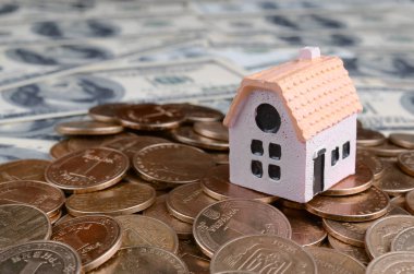 Büyük paralar üzerinde mini ev modeli arka plan olarak birçok dolar faturaları yığını