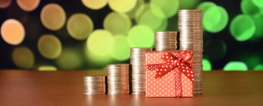 Renkli bokeh arka planda küçük kırmızı hediye kutusu ve altın sikke yığınları