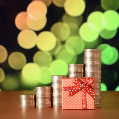 Renkli bokeh arka planda küçük kırmızı hediye kutusu ve altın sikke yığınları