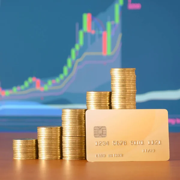 Stacks of golden coins and credit card on the background of growth chart on display