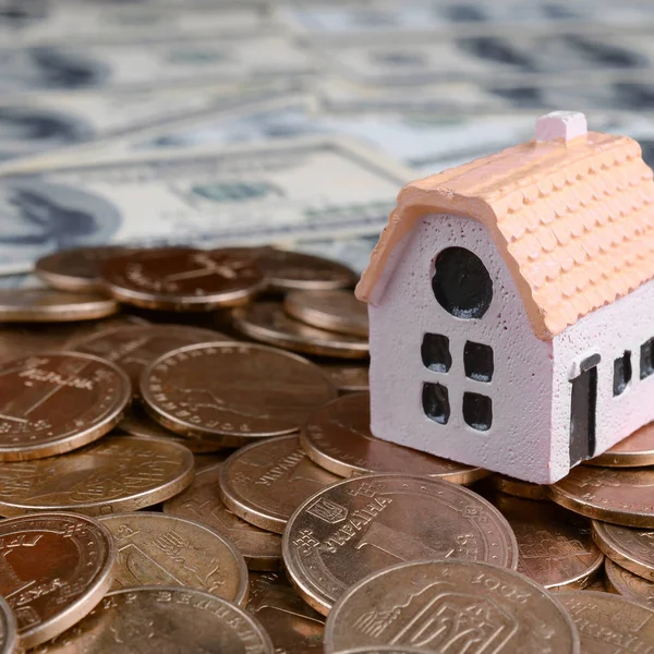 Mini ház modell nagy érmék verem a sok dollárszámlák a háttérben — Stock Fotó