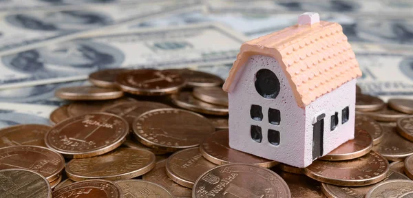 Mini hus modell på stora mynt stack på många dollar sedlar som bakgrund — Stockfoto