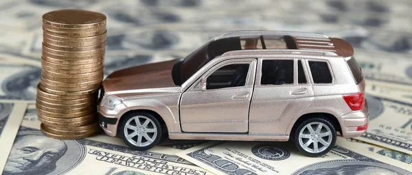玩具汽车在100美元钞票和一叠金币的背景下意外 — 图库照片