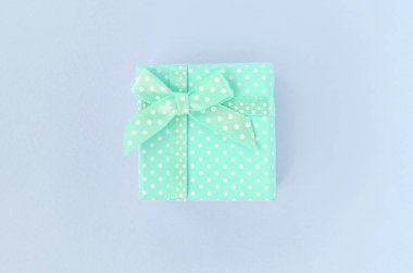 Kurdeleli küçük mavi hediye kutusu mor bir arka plan üzerinde yatıyor