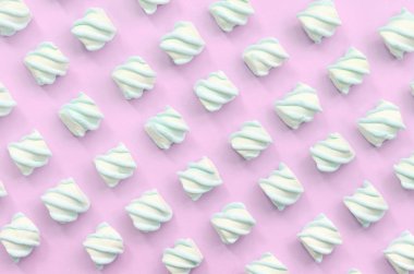 Renkli marshmallow pembe kağıt arka plan üzerine serilmiş