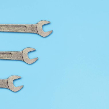 Üç metalik spanners moda pastel mavi renkli kağıt doku arka plan üzerinde yalan