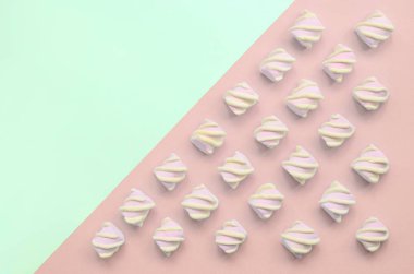 Renkli marshmallow turkuaz ve pembe kağıt arka plan üzerine serilmiş