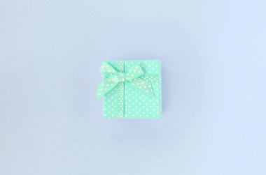 Kurdeleli küçük mavi hediye kutusu mor bir arka plan üzerinde yatıyor