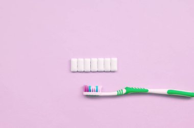 Diş fırçası ve sakız pastel pembe arka plan üzerinde yalan