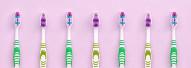 Bir çok diş fırçası pastel pembe arka plan üzerinde yatıyor