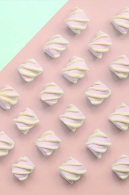Renkli marshmallow turkuaz ve pembe kağıt arka plan üzerine serilmiş
