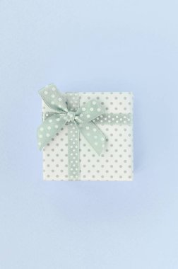 Kurdeleli küçük beyaz hediye kutusu mor bir arka plan üzerinde yatıyor