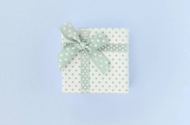 Kurdeleli küçük beyaz hediye kutusu mor bir arka plan üzerinde yatıyor