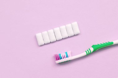 Diş fırçası ve sakız pastel pembe arka plan üzerinde yalan