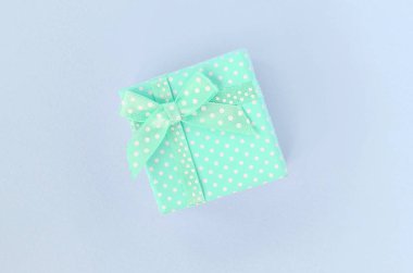 Kurdeleli küçük mavi hediye kutusu mor bir arka plan üzerinde yatıyor