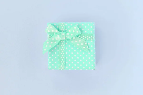 Small blue gift box with ribbon lies on a violet background — Stock Photo, Image