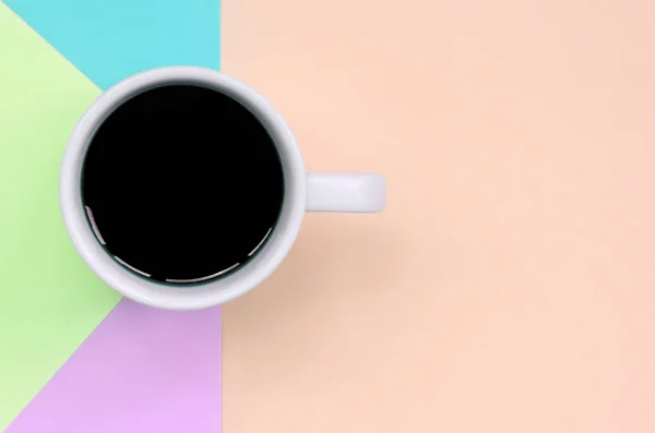 Pequeña taza de café blanco en el fondo de textura de la moda pastel rosa, azul, coral y papel de colores de cal — Foto de Stock