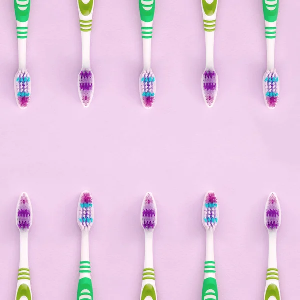 A lot of toothbrushes lie on a pastel pink background — Stock Photo, Image