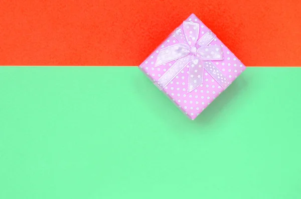 小粉红色礼品盒躺在时尚柔和的绿松石和红色纸的纹理背景 — 图库照片