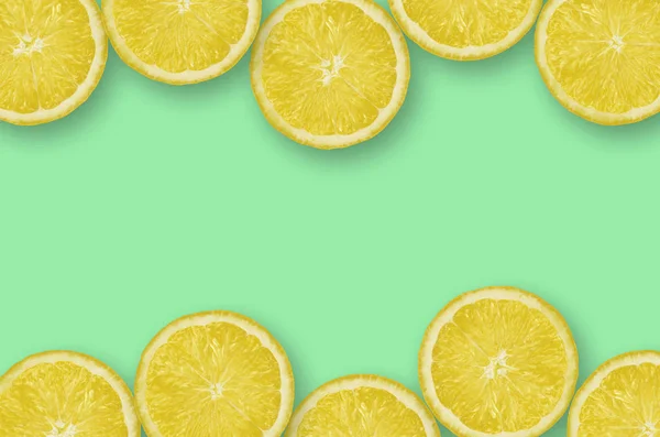 Frame of yellow lemon citrus slices on bright lime background — Stock Photo, Image