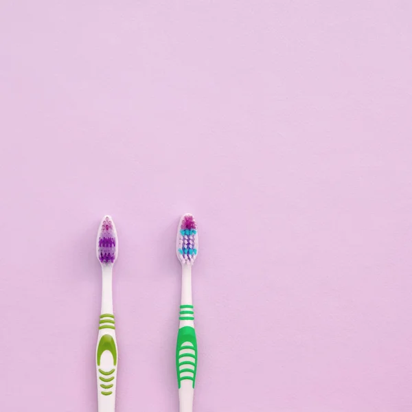 Дві зубні щітки лежать на пастельно-рожевому тлі — стокове фото