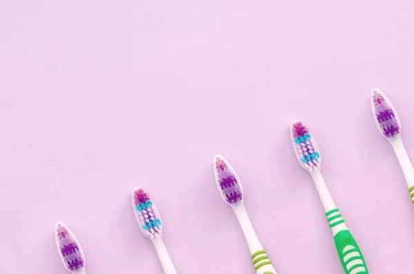 Багато зубних щіток лежать на пастельно-рожевому тлі — стокове фото