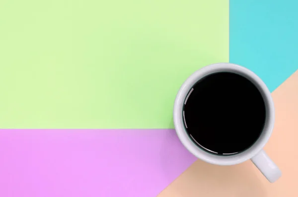 Pequeña taza de café blanco en el fondo de textura de la moda pastel rosa, azul, coral y papel de colores de cal — Foto de Stock