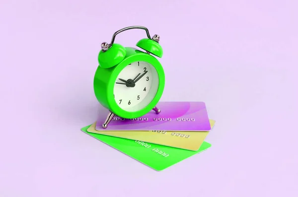 Small alarm clock lies on colored credit cards — Stock Photo, Image