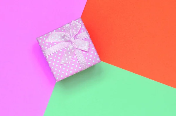 小粉红色礼品盒躺在时尚柔和的绿松石，红色和粉红色纸的纹理背景 — 图库照片