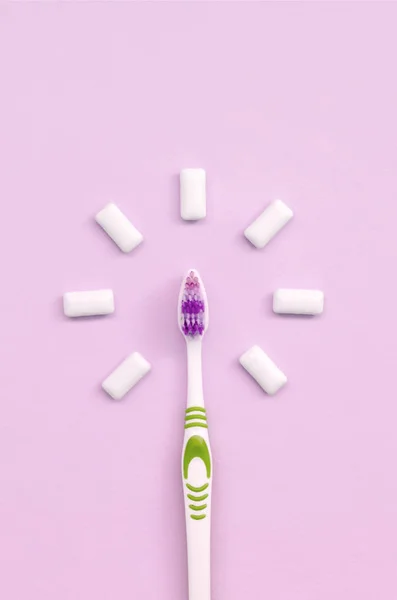 Toothbrush and chewing gums lie on a pastel pink background — Stock Photo, Image